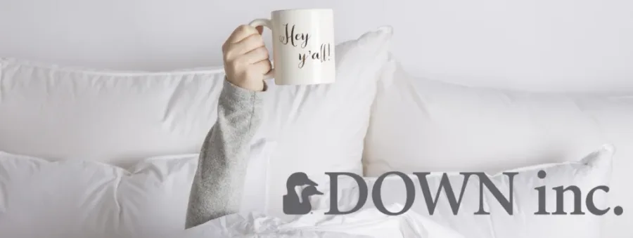 hand holding cup that says hey y'all surrounded by pillows with down inc logo